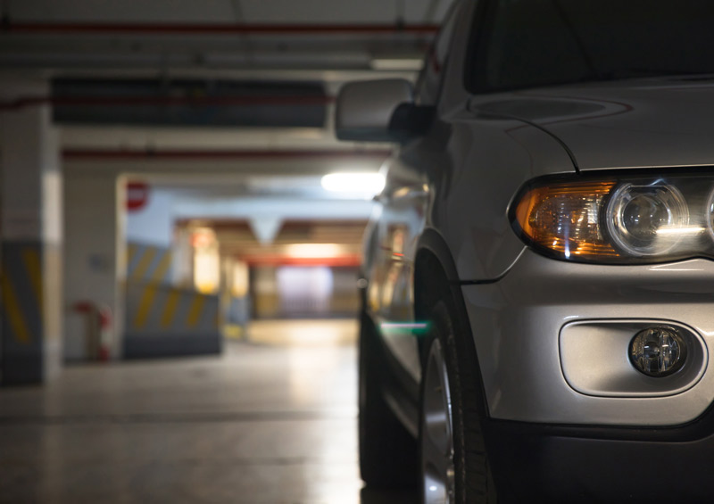 Carro parado em estacionamento de prédio, à noite.,