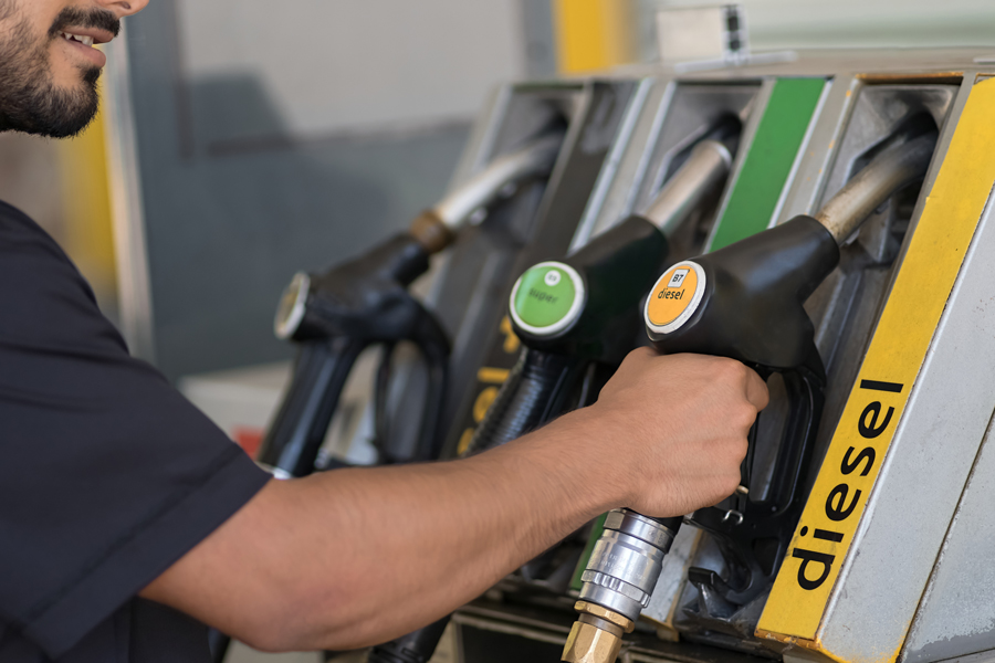 Frentista segurando mangueira de abastecimento de diesel.