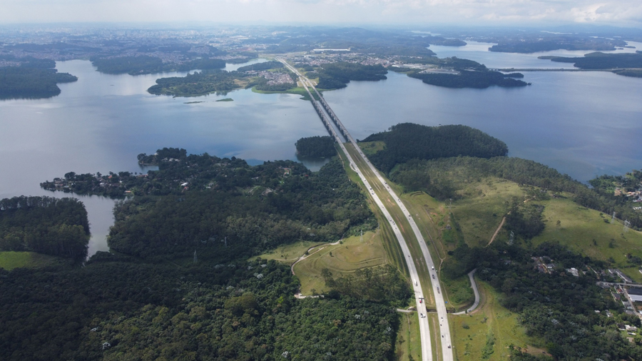 Foto aérea de infraestrutura rodoviária brasileira, rodovia passando por cima de lago.